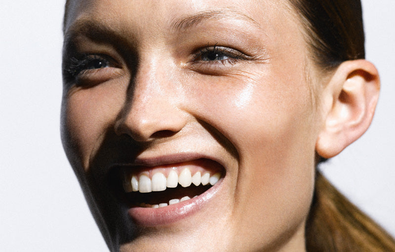 une femme au grand sourire, portant un maquillage anti-fatigue