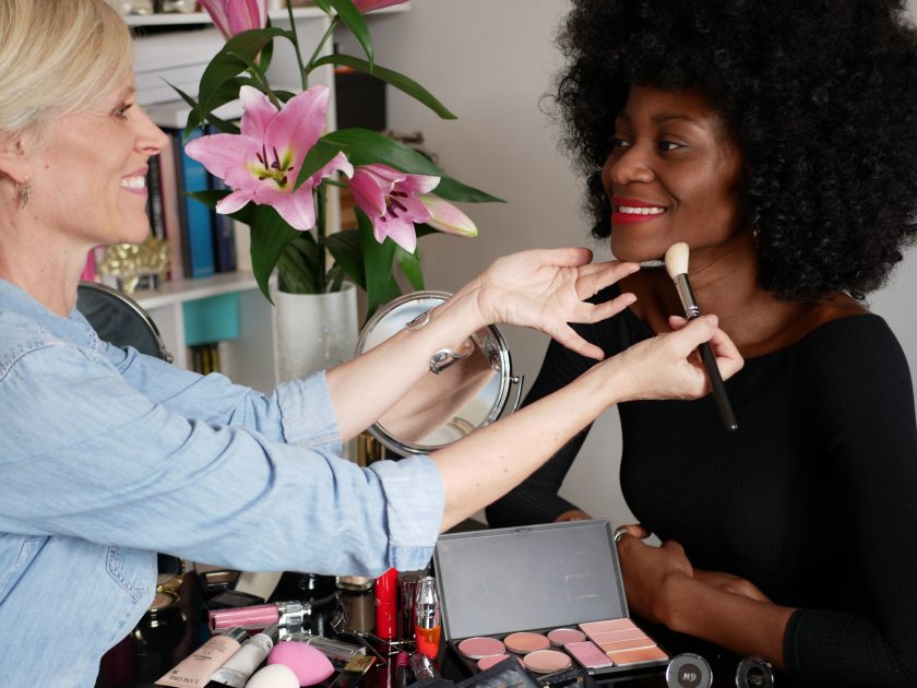 Une jeune femme à la peau noire est en train de se faire maquiller par Louise Wittlich, maquilleuse pro et coach beauté, lors de son cours de maquillage + shopping