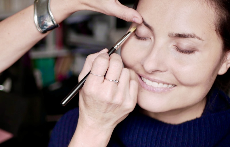 A young woman is being made up by Louise Wittlich, professionnal makeup artist and beauty coach