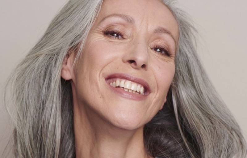 Une belle femme mature au grand sourire, portant un maquillage naturel et anti-âge de la bouche