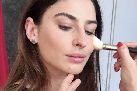 A young women, a wedding guest, is being made up in a natural style.