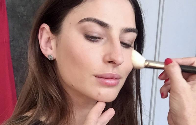 A young women, a wedding guest, is being made up in a natural style.